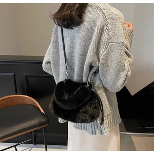 Détail du sac bandoulière en fausse fourrure noire avec lanière en cuir et boucle