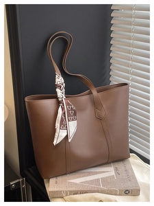 Detail of dark brown leather tote bag featuring a decorative bear print silk scarf
