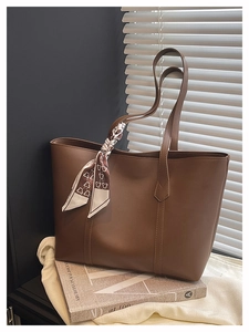 Close-up of large brown tote bag featuring matte synthetic leather and a stylish printed scarf