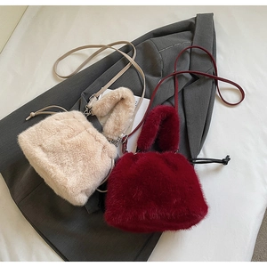 Détail de sacs seaux en fausse fourrure crème et bordeaux avec poignées en peluche