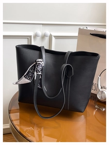 Detailed view of black faux leather tote bag with heart pattern scarf on mirrored table