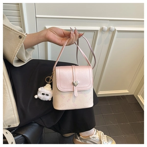 Detail of crossbody bucket bag with heart metal buckle and plush cat charm decoration