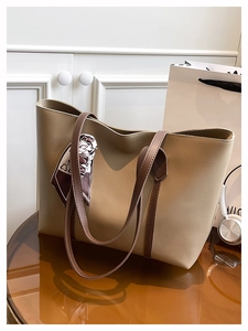 Close-up of large khaki tote bag featuring dark brown straps and a decorative silk scarf