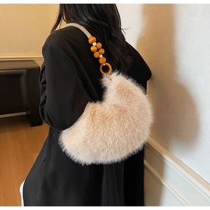 Détail du sac à main en peluche beige avec bandoulière perlée orange porté à l'épaule