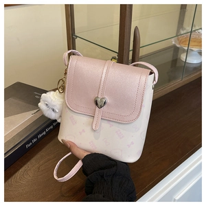 Close-up of pink and white crossbody bucket bag with silver heart buckle and cat charm