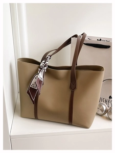 Detail of khaki tote bag with dark brown handles and a decorative printed silk scarf decoration
