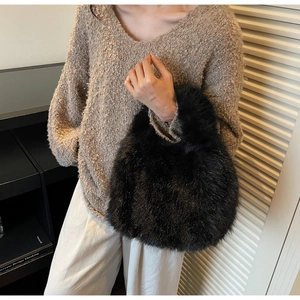 Détail du sac à main en fausse fourrure noire douce porté avec un pull en tricot chaud