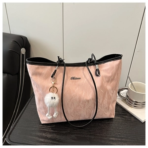 Detailed texture of pink pleated tote bag with black handles and plush charm accessory