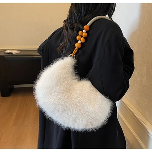 Détail du sac croissant en fausse fourrure blanche avec bandoulière perlée sur manteau noir