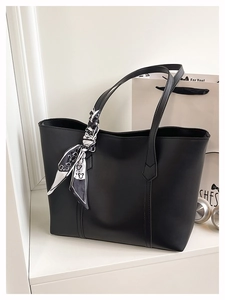 Detail of black leather tote bag with printed silk scarf handle and matte texture