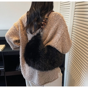 Détail d'un sac bandoulière en fausse fourrure noire avec sangle en perles de bois