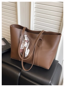 Close-up of large dark brown leather tote bag with a decorative bear print silk scarf