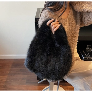Détail d'un sac à main noir en fausse fourrure porté par un mannequin en pull beige
