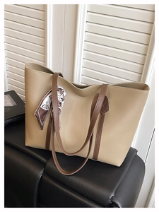 Close-up of beige leather tote bag featuring a decorative scarf and dual brown shoulder straps