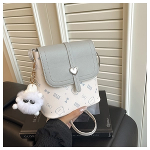 Detail of grey bucket bag featuring cat patterns, heart clasp, and plush kitten charm