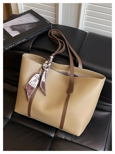 Close-up of beige tote bag with dark brown straps and decorative printed silk scarf