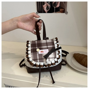 Detail of sweet pleated bag with brown plaid flap, five-point star, and pink cherry label