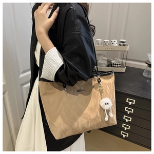 Detail of light brown tote bag with pleated texture and plush monster charm