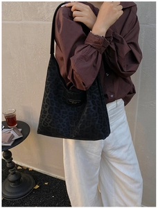 Detail of black leopard embossed hobo bag with fashion logo on stylish casual outfit