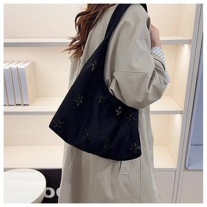 Detail view of large hollow floral tote bag worn over a beige coat for daily fashion