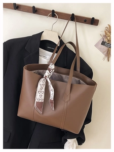 Close-up of brown PU leather tote bag with a silk scarf detail on a black suit