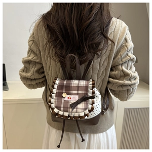 Detail of a brown plaid mini backpack with lace ruffles and cute cherry patch
