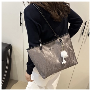 Detail of silver metallic tote bag with pleated texture and white fluffy keychain