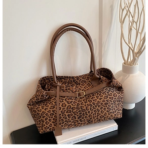Detail of leopard print tote bag with brown leather handles on a minimalist desk