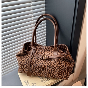 Detail of leopard print tote bag with brown leather handles on a sunlit windowsill