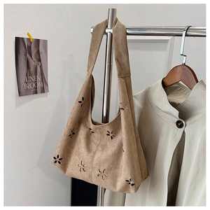 Close-up of laser-cut flower patterns on light brown suede hollow tote bag surface