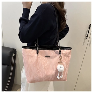 Detail of pink pleated tote bag featuring black straps and a white fluffy monster charm