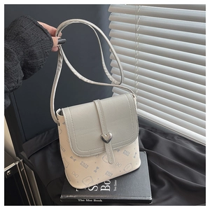 Close-up of heart-shaped metal buckle on cream and gray leather bucket bag with cat prints