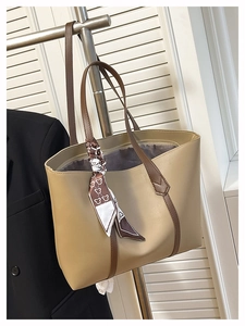 Detail of large beige tote bag with brown straps and bear print decorative scarf