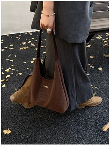 Detail of suede leopard print tote bag with leather logo patch on autumn street background