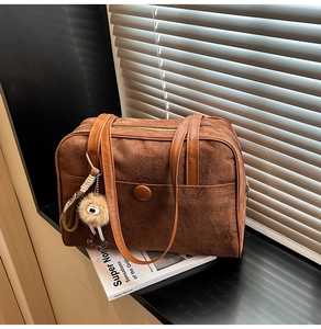 Detail of dark brown suede tote bag featuring a round clasp pocket and plush monster charm