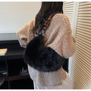 Détail du sac hobo en fausse fourrure noire avec une bandoulière en perles de bois marron