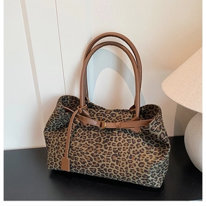 Macro view of leopard print tote bag featuring brown leather handles and gold metal buckle