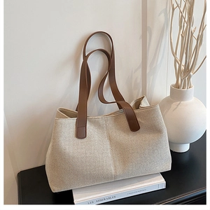 Detail of high-capacity canvas tote bag with brown leather handles and premium stitching