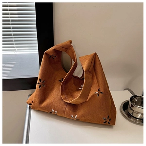 Close-up of caramel suede tote bag featuring intricate laser-cut floral patterns and texture