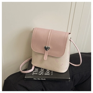 Detail of pink and beige crossbody bag featuring a silver heart-shaped metal buckle
