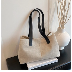 Detail of minimalist beige canvas tote bag with black leather straps and textured fabric