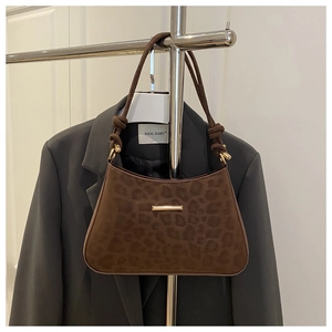 Détail du sac léopard avec fermoir doré et bandoulière à nœud sur une veste grise