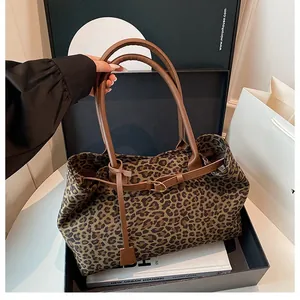 Detail of leopard print tote bag with brown leather handles and gold metal buckle