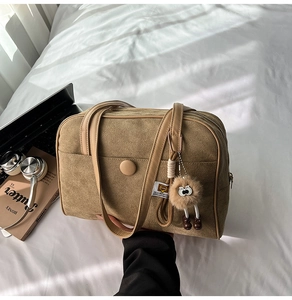 Detailed texture of brown suede shoulder bag with a cute plush mascot accessory