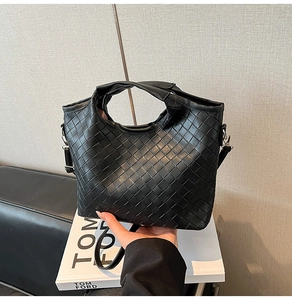 Detail view of black woven texture tote bag featuring high-quality faux leather craftsmanship