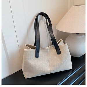 Detail of minimalist canvas tote with contrast leather handles on a sleek modern surface