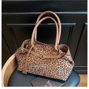 Detail of leopard print tote bag featuring brown leather straps and gold buckle buckle