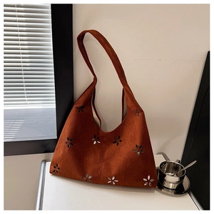 Detailed close-up of brown suede hobo bag featuring intricate laser-cut floral patterns