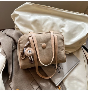 Detail of large suede shoulder bag with light leather strap and fuzzy eye charm
