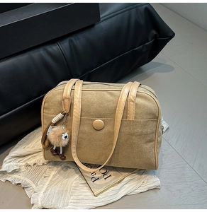Detail of khaki suede shoulder bag with leather strap and brown pompom charm